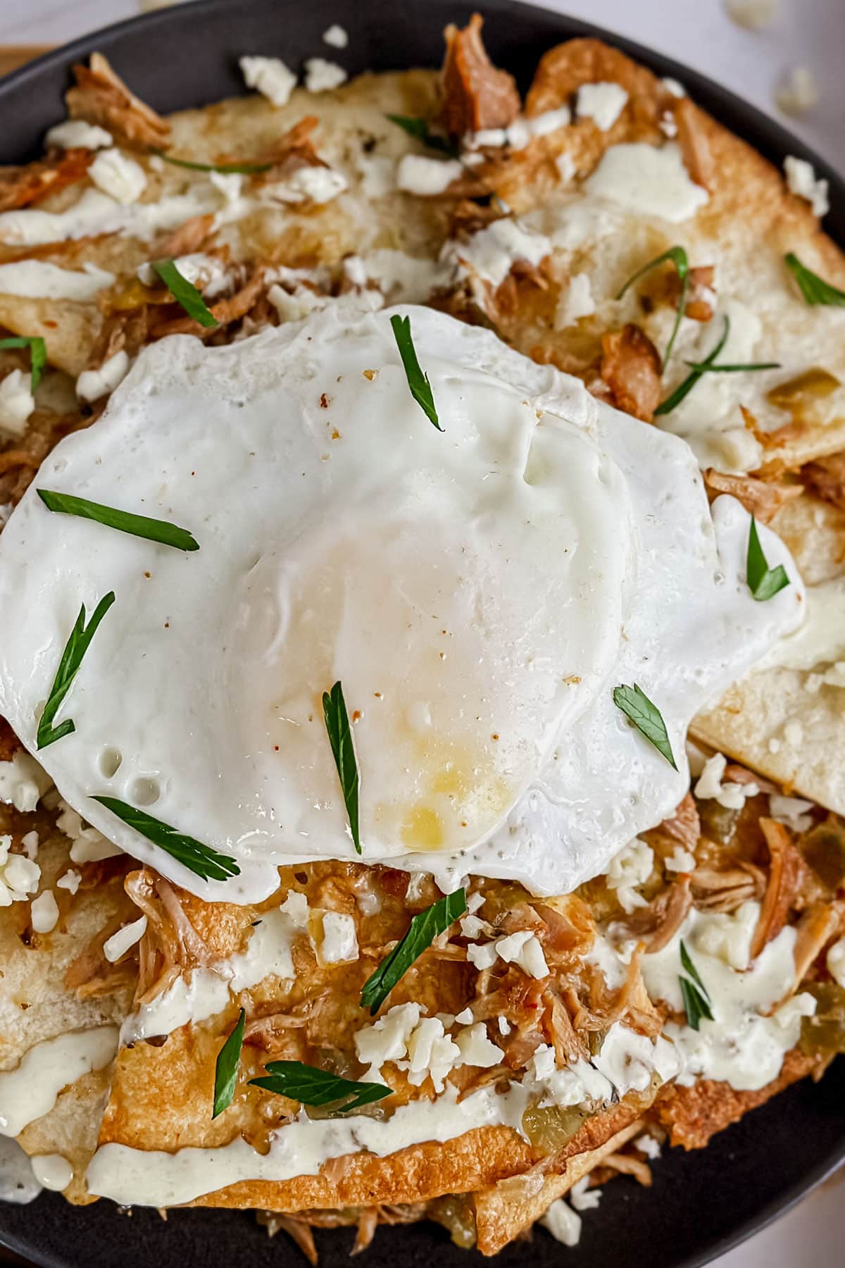 Air Fryer Chilaquiles topped with sunny side up, cheese, and parsley