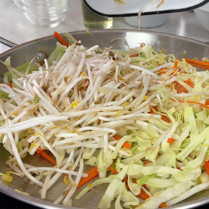 Assorted sliced veggies for egg roll recipe in a large pan.
