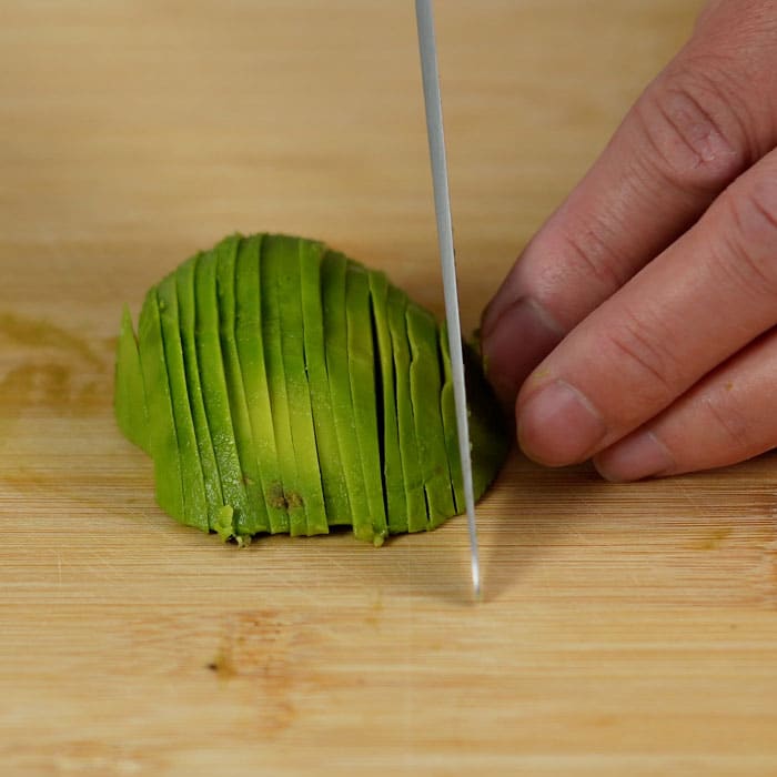 Slicing avocado into thin strips.