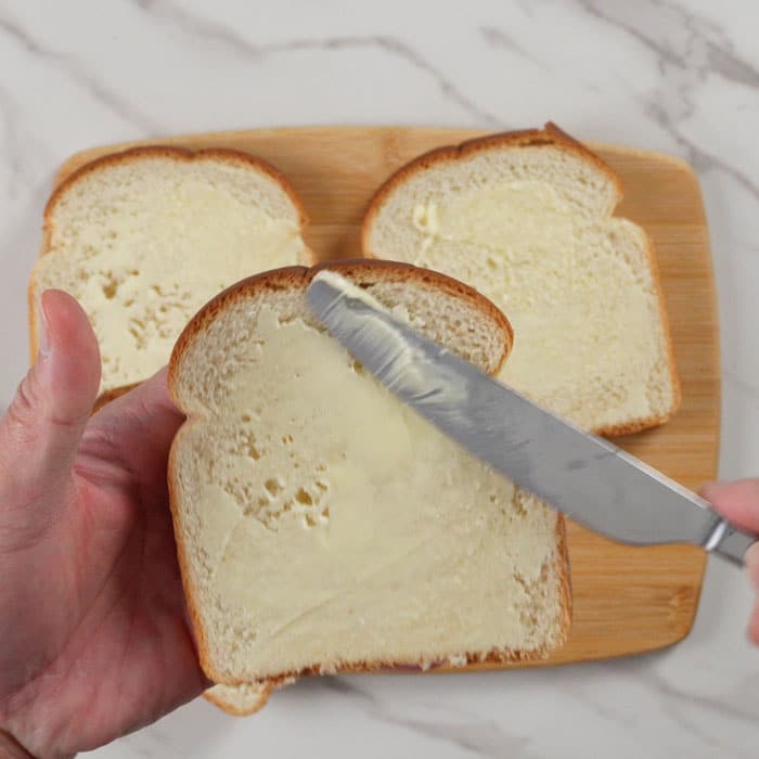 Spreading butter onto bread with butter knife.
