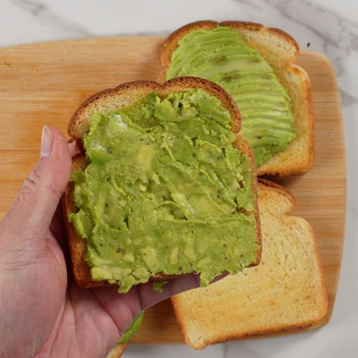 Spreading mashed avocado on air-fried toast.