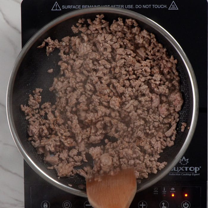 Cooking ground pork in a non-stick pan.