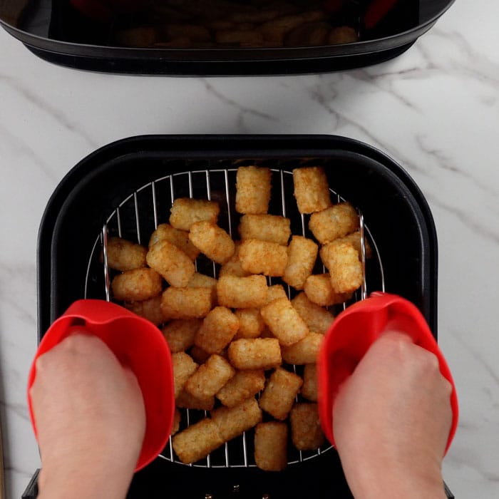 Placing tater tots in air fryer.