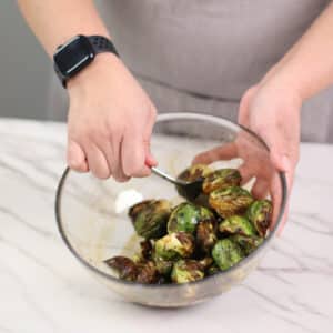tossing air-fried brussels sprouts in balsamic honey glaze
