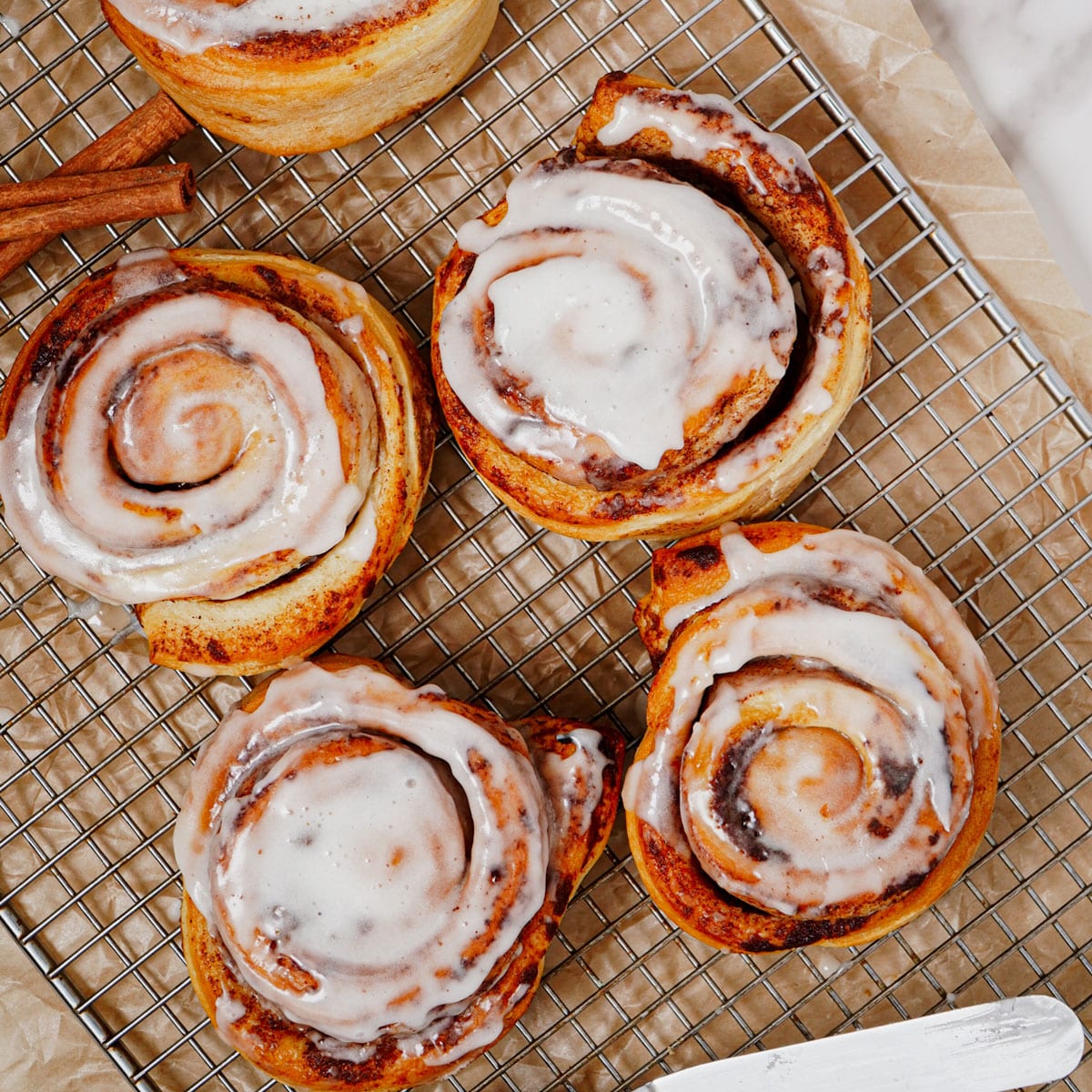 Air fried Pillsbury Grands cinnamon rolls with original icing on a cooling rack.