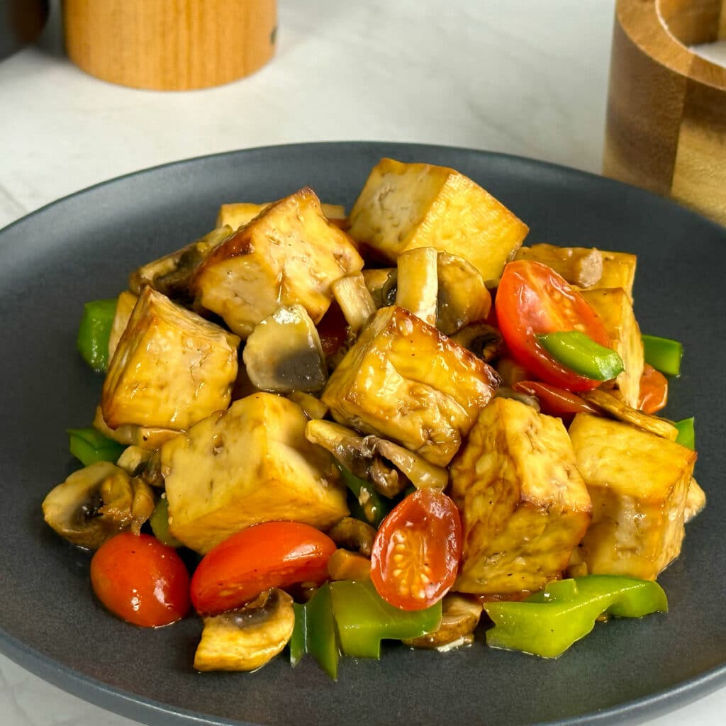 Air fried tofu and veggies served on a black plate