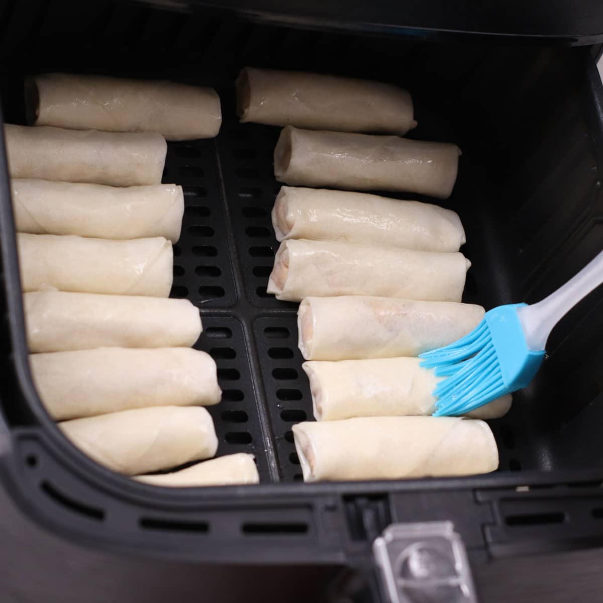 Brushing spring rolls with cooking oil