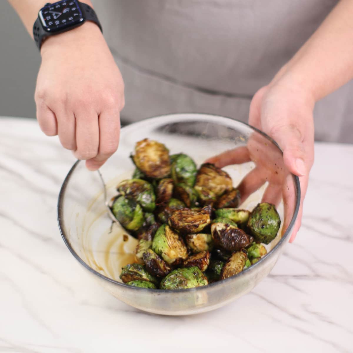 Coating brussel sprouts with balsamic honey glaze in a large bowl