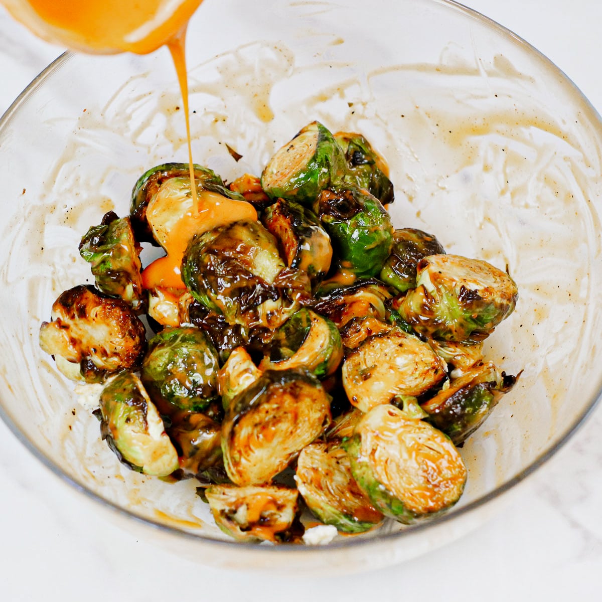 Coating air fried Brussels sprouts with buffalo sauce