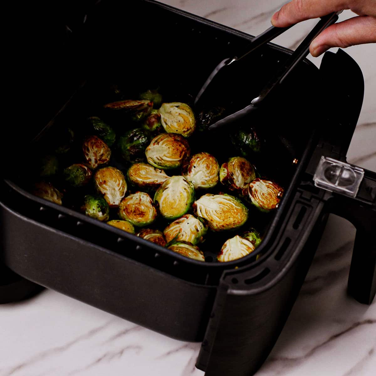 Flipping roasted garlic parmesan Brussels sprouts in air fryer