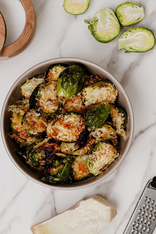 Garlic parmesan Brussels sprouts air fryer recipe bite shot, served in a grey bowl.