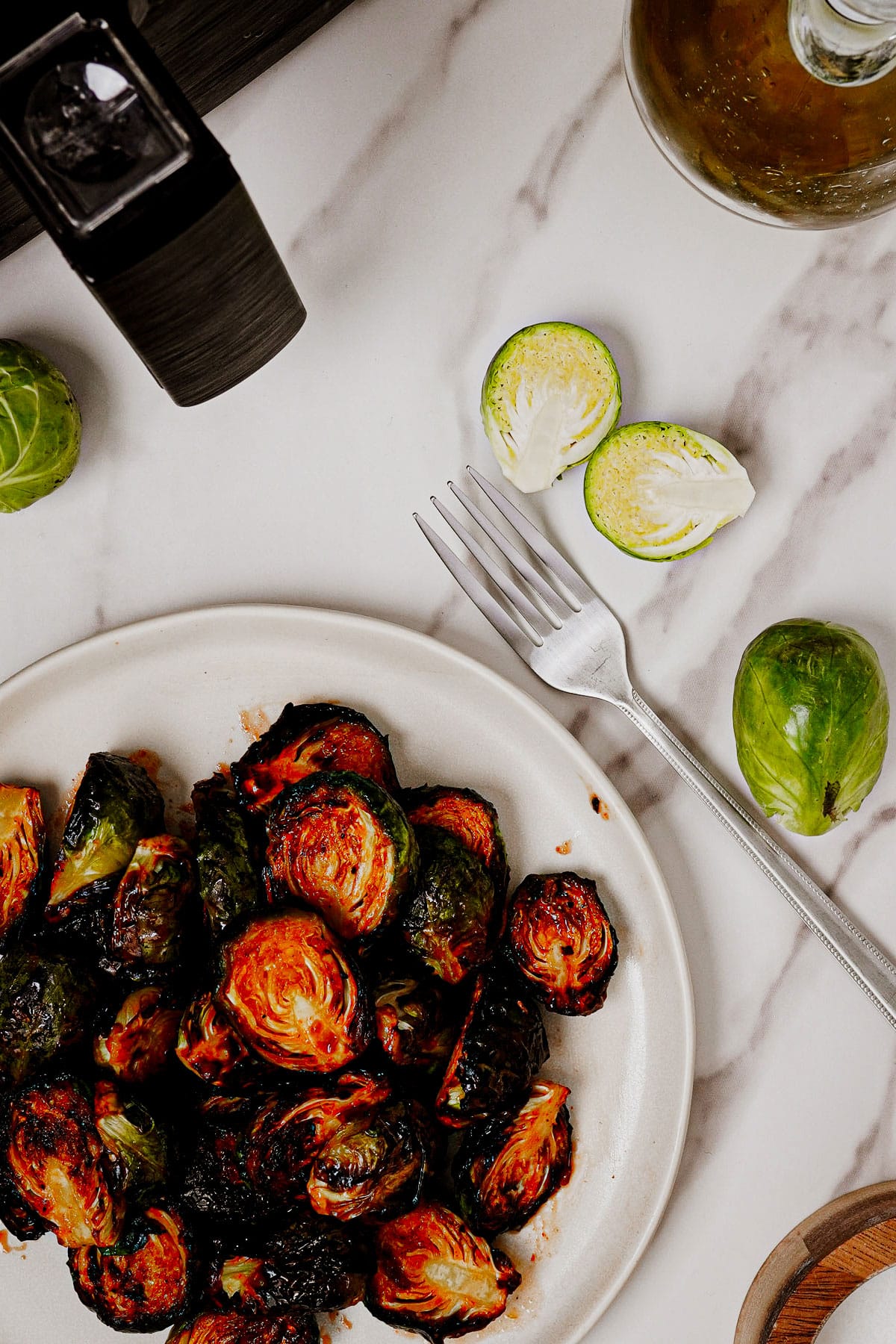 Honey sriracha Brussels sprouts air fryer recipe bite shot, served in a white plate with a fork on the side