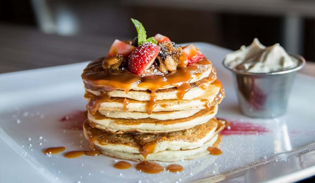 stacked pancakes with caramel, nuts and strawberry