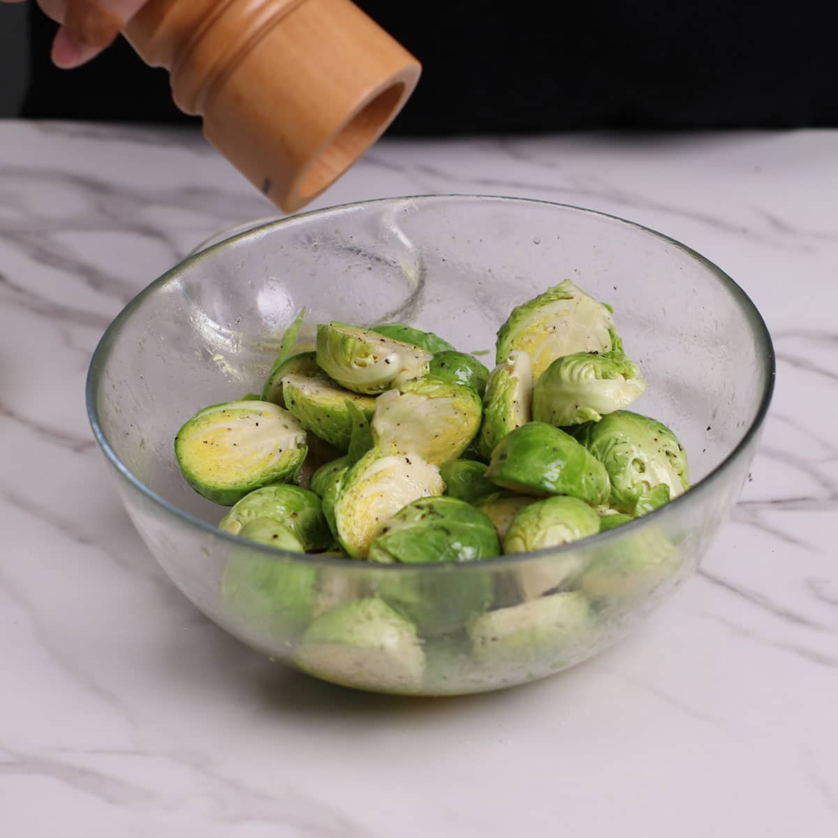 Seasoning Brussel Sprouts in a large bowl