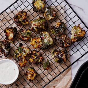 Cooked smashed Brussels sprouts air fryer recipe served on a cooling rack with ranch dipping sauce