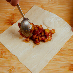 Adding apple pie filling to egg roll wrapper.