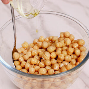 Coating garbanzo beans with oil in a medium bowl.