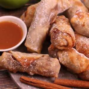 Air fried apple pie egg rolls with caramel dipping sauce on the side.