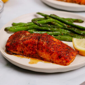 Air fryer cajun salmon served with green beans and lemon slices.