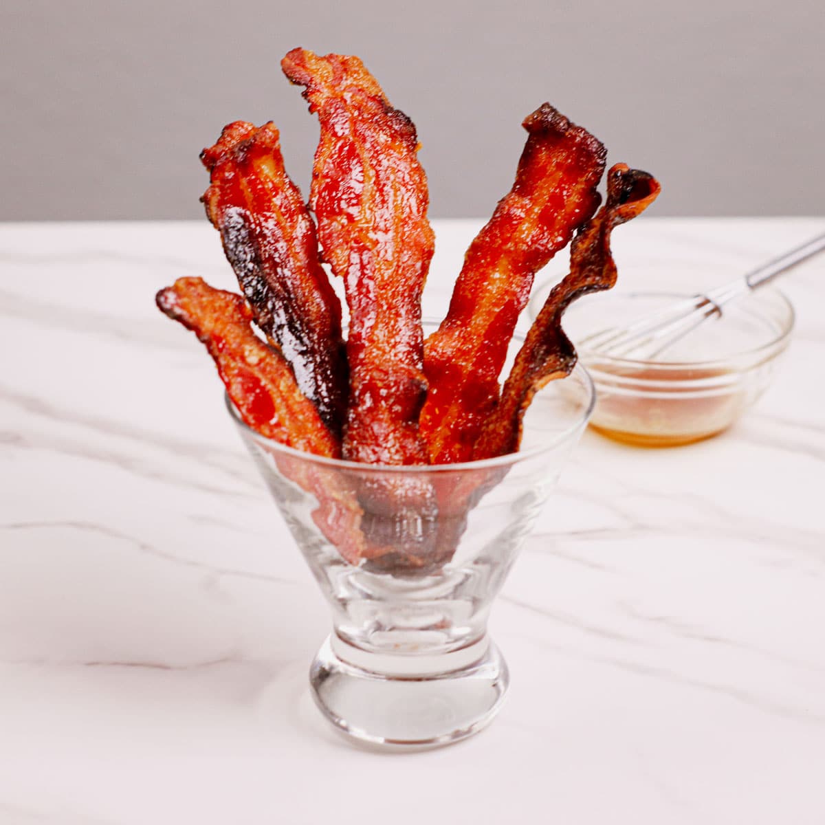 Air fried candied bacon served in a cocktail glass.