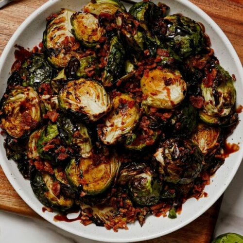 Air fryer Brussels sprouts recipe topped with bacon bits, with balsamic glaze dip on the side.