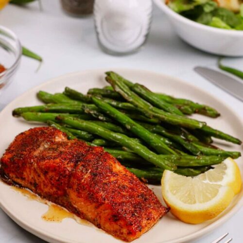 Air fryer cajun salmon recipe bite shot, served with green beans and lemon slices.