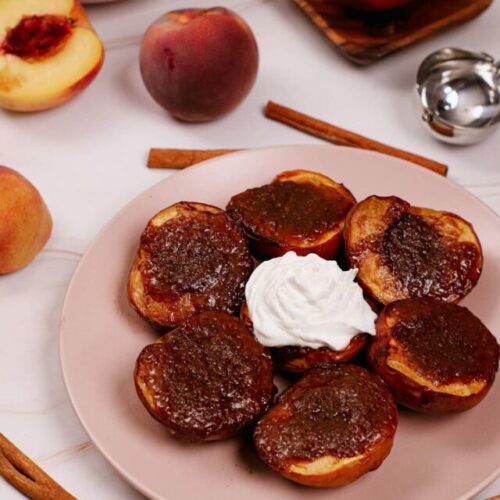 Air fryer grilled peaches bite shot, served on a plate with one peach topped with whipped cream.