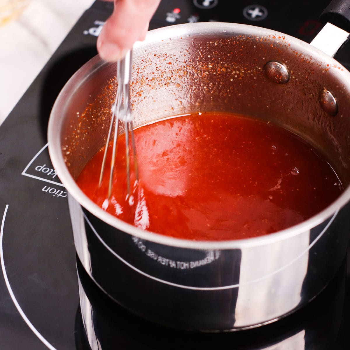 Homemade barbecue sauce, mixing with small whisk.