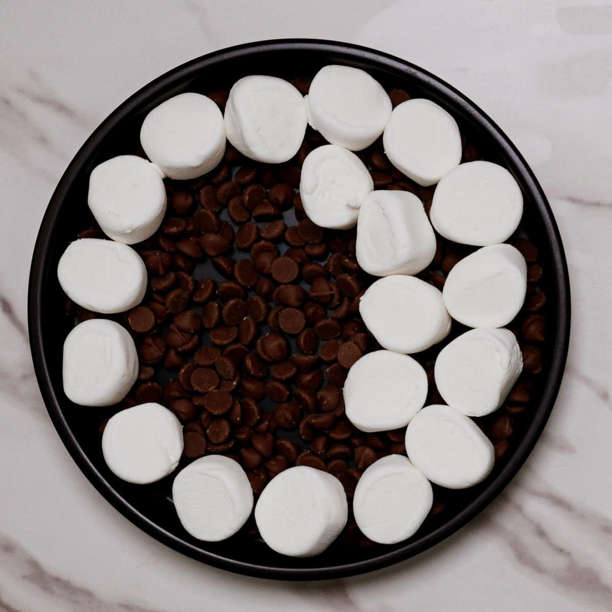Layering chocolate chips and marshmallows on an air fryer pizza pan.