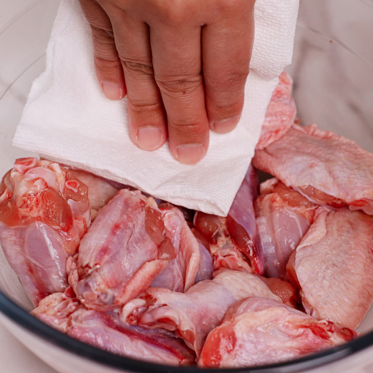 Patting chicken wings dry with paper towel.