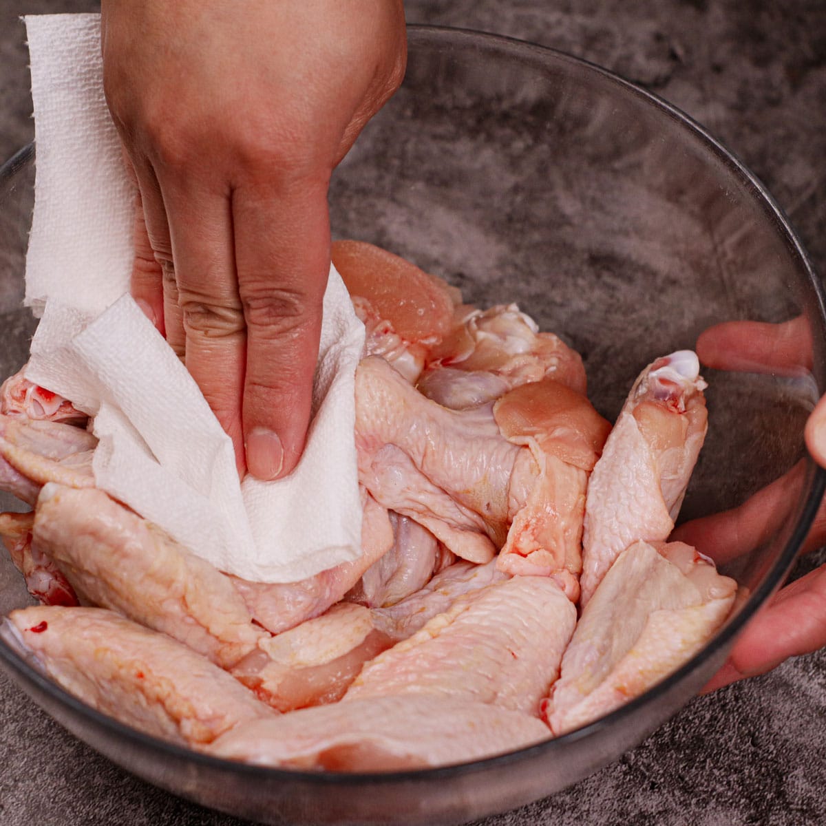 Patting chicken wings dry with a paper towel