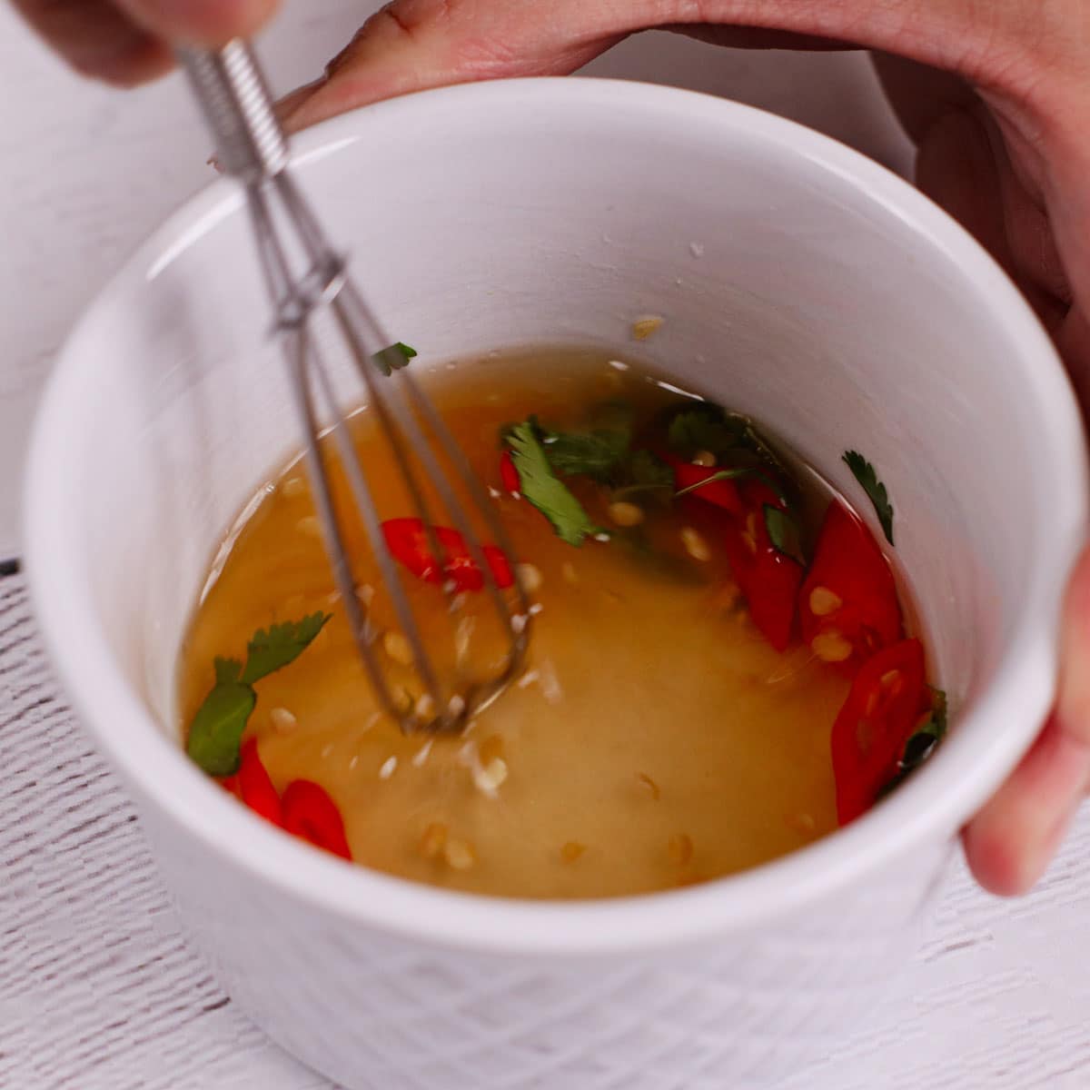 Mixing thai spicy dip in a ramekin bowl