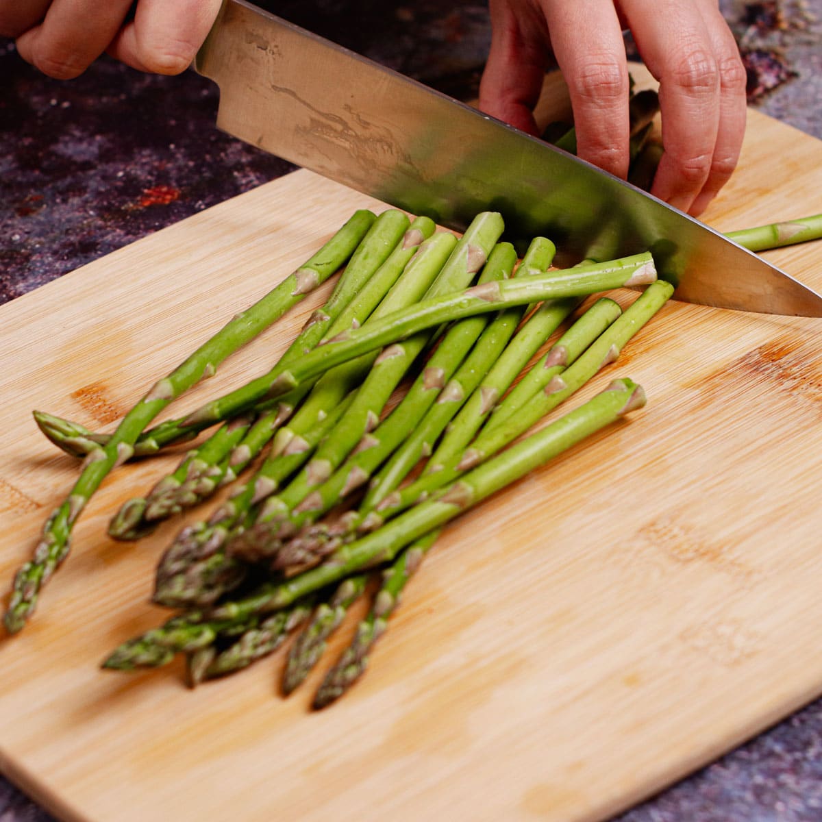 Trimming asparagus tough ends on a chopping board.