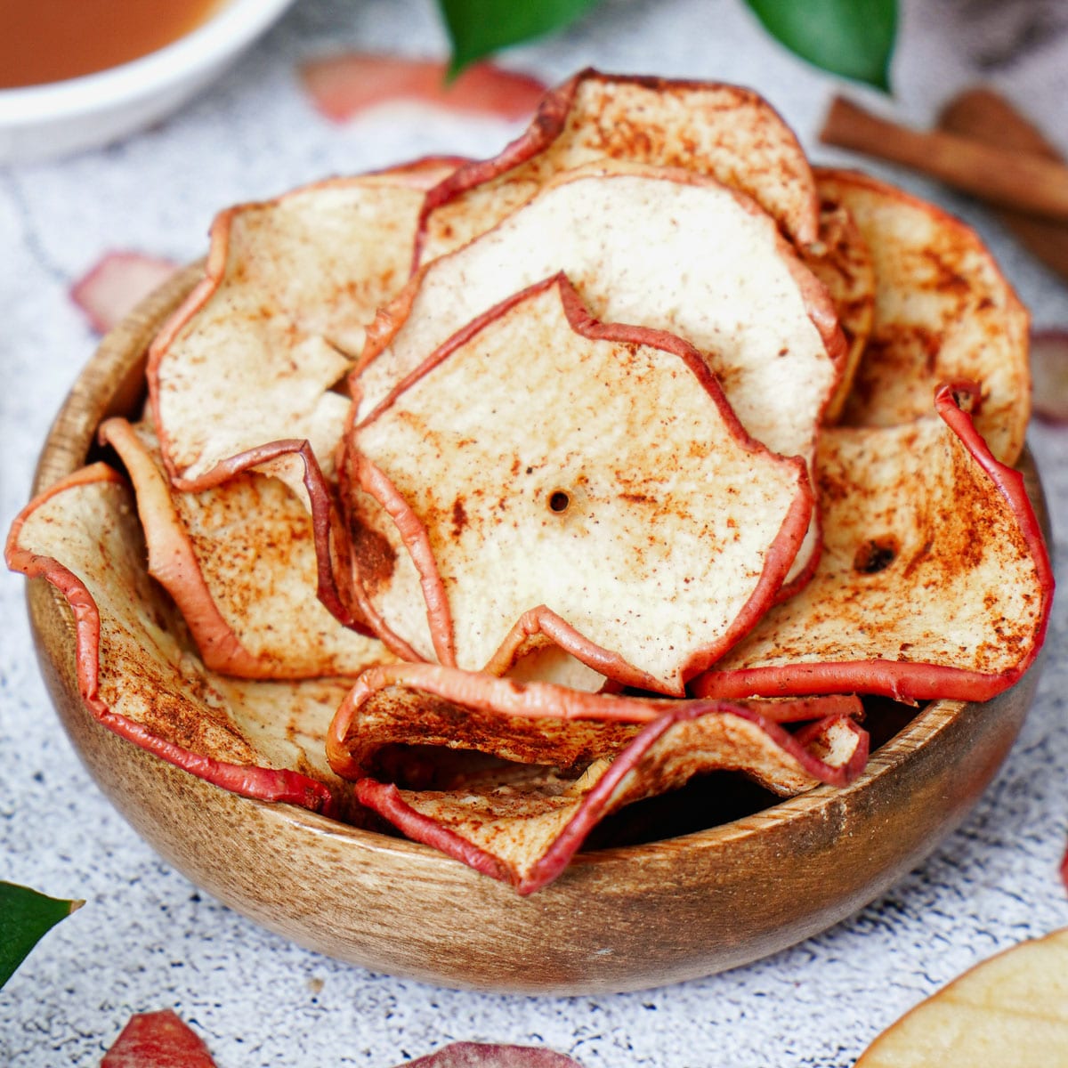 Air fried apple chips in a small wooden bowl.