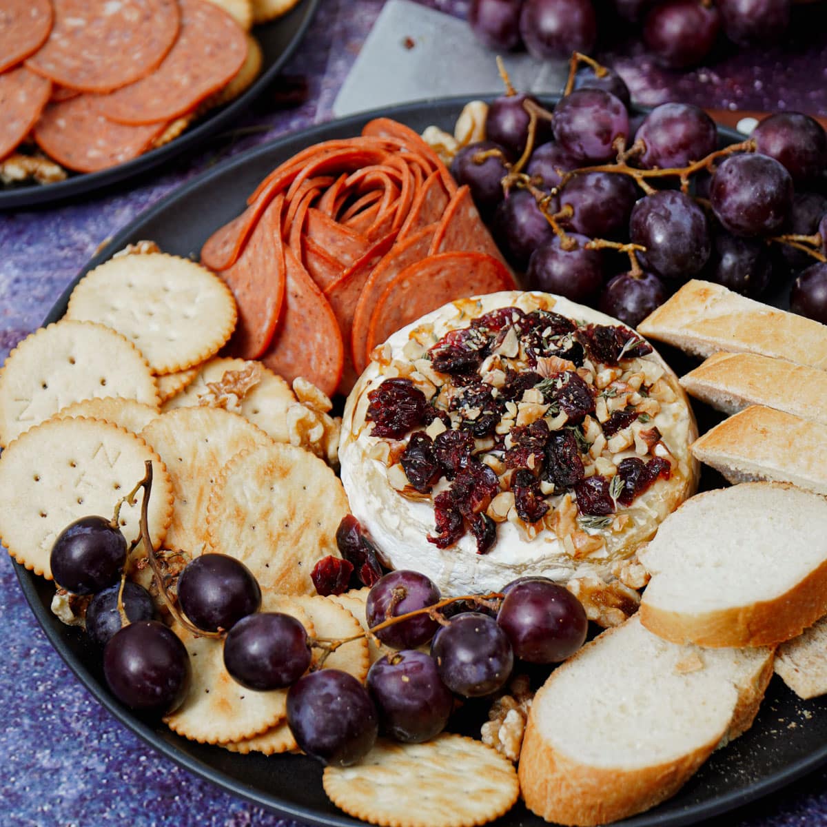 Air fried Brie cheese with baguette slices, grapes, crackers, and pepperoni.