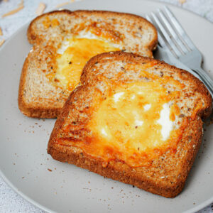 Air fried egg toasts, 2 slices, on a plate with fork and knife.