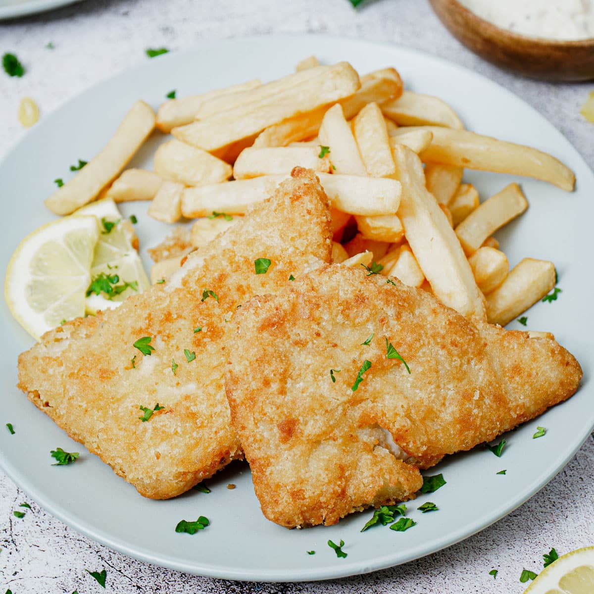 Air fried frozen fish and chips with lemon slices.