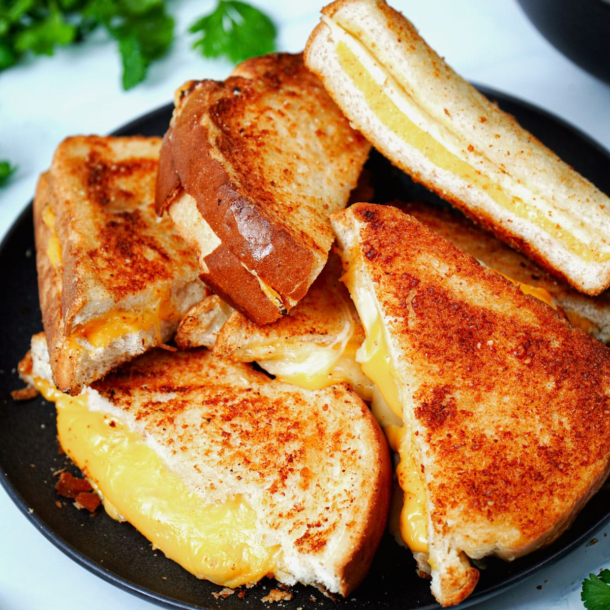 Air fried grilled cheese sandwich, stacked on a black plate.