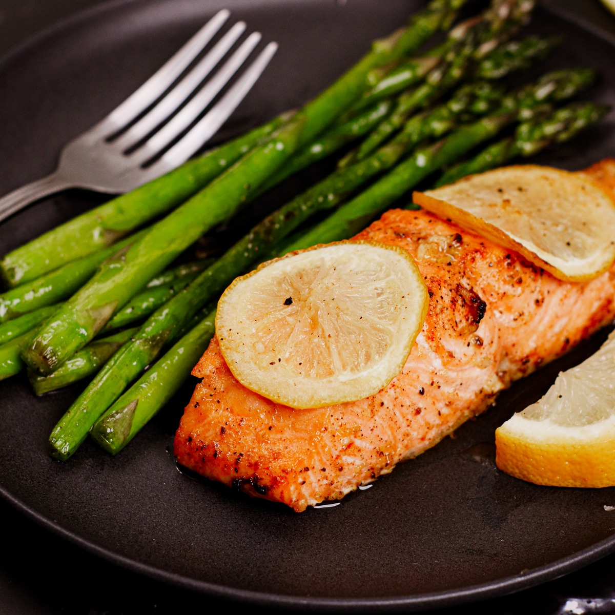 Air fried lemon salmon served with lemon slices and roasted asparagus