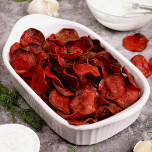 Air fried pepperoni chips served in a white baking dish with yogurt dip