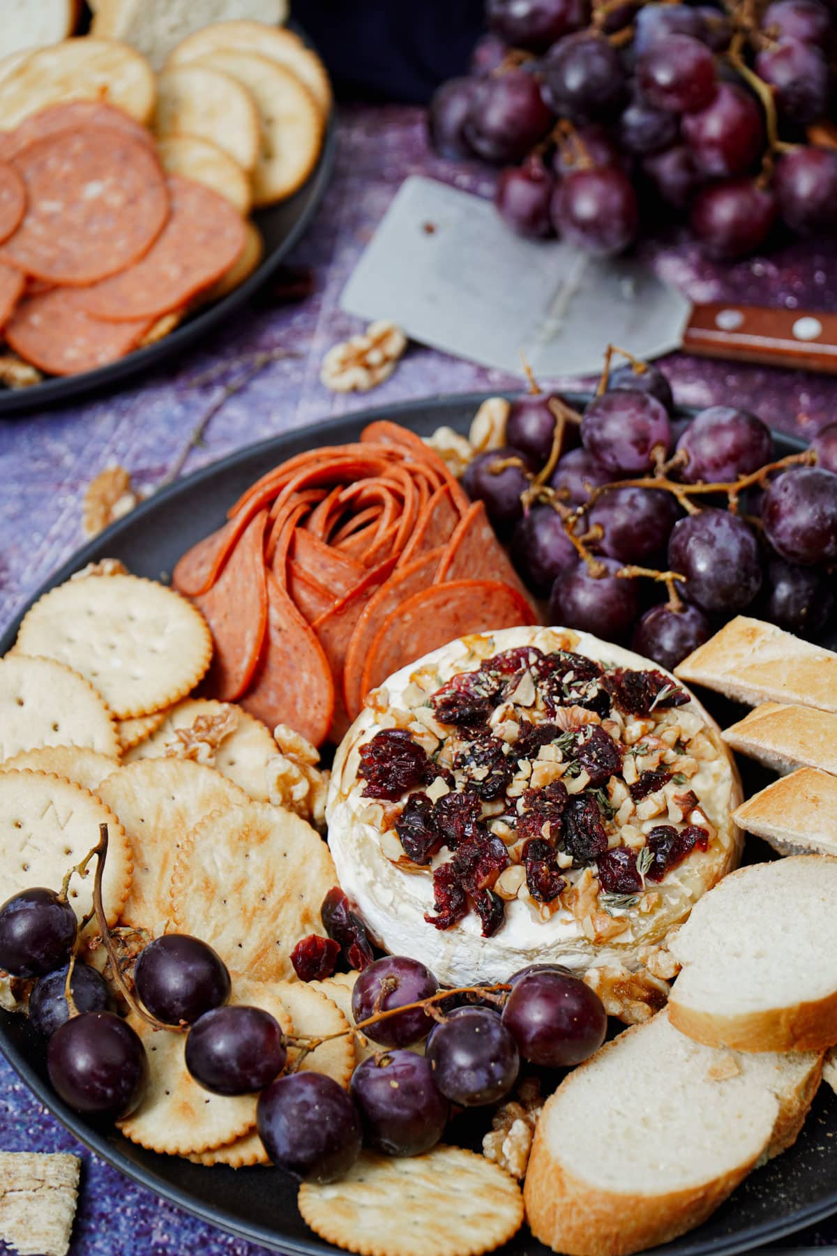Air Fryer Baked Brie recipe bite shot, with baguette slices, grapes, crackers, and pepperoni.