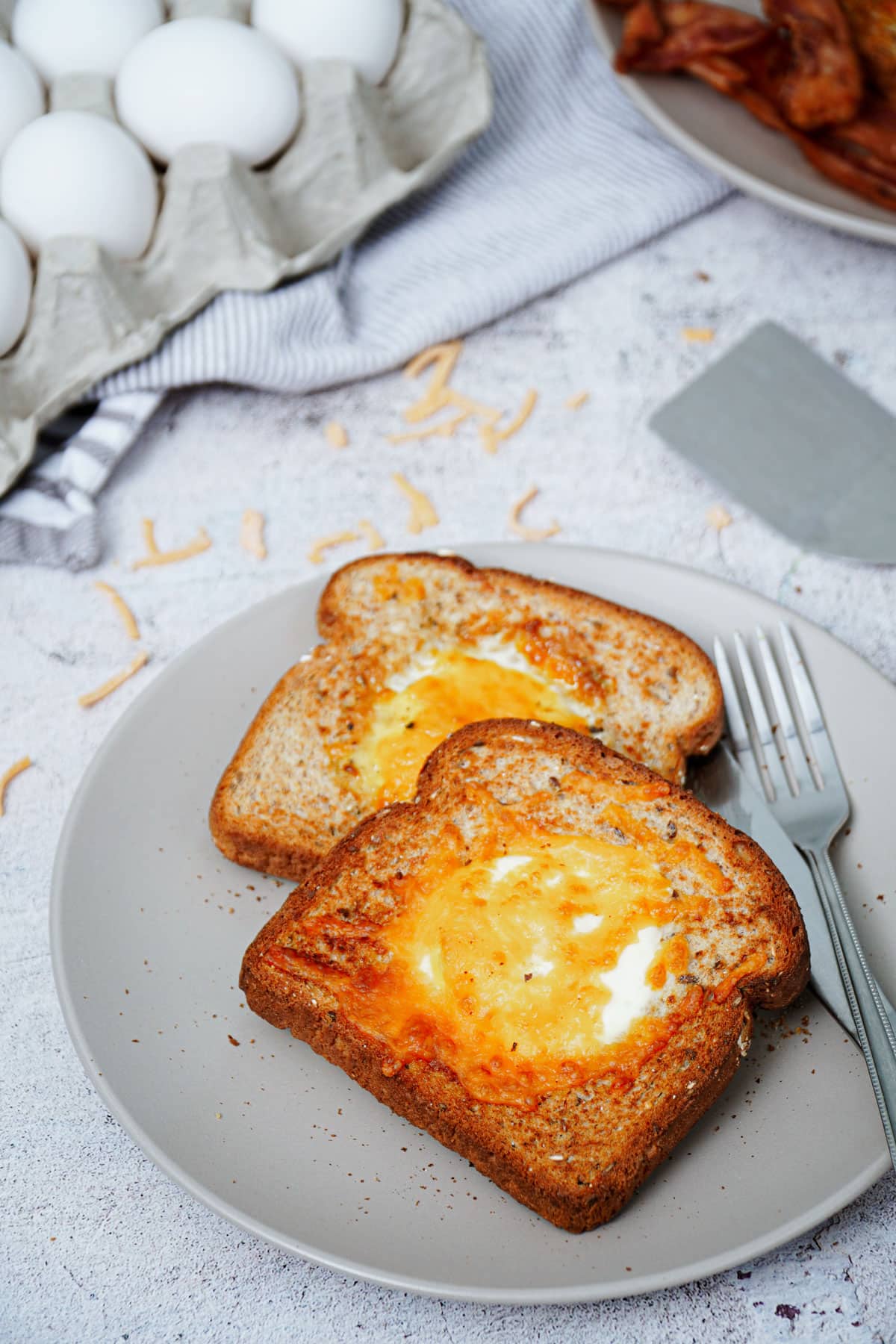 Air fryer egg toast recipe bite shot, 2 slices served on a plate with knife and fork.