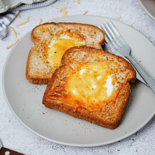 2 slices of air fryer egg toast served on a plate with a knife and a fork.