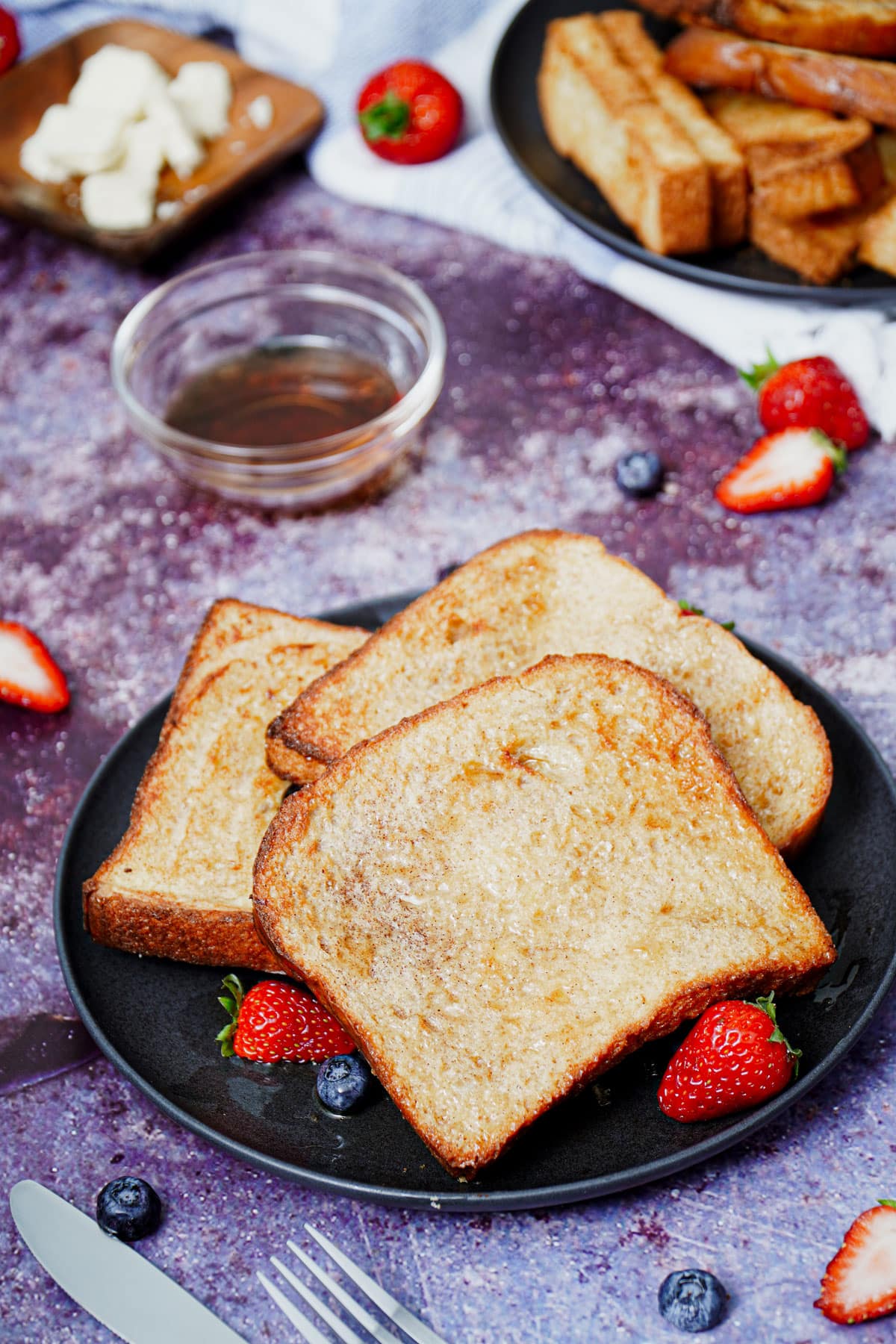 Air fryer French toast recipe bite shot served with berries and maple syrup.