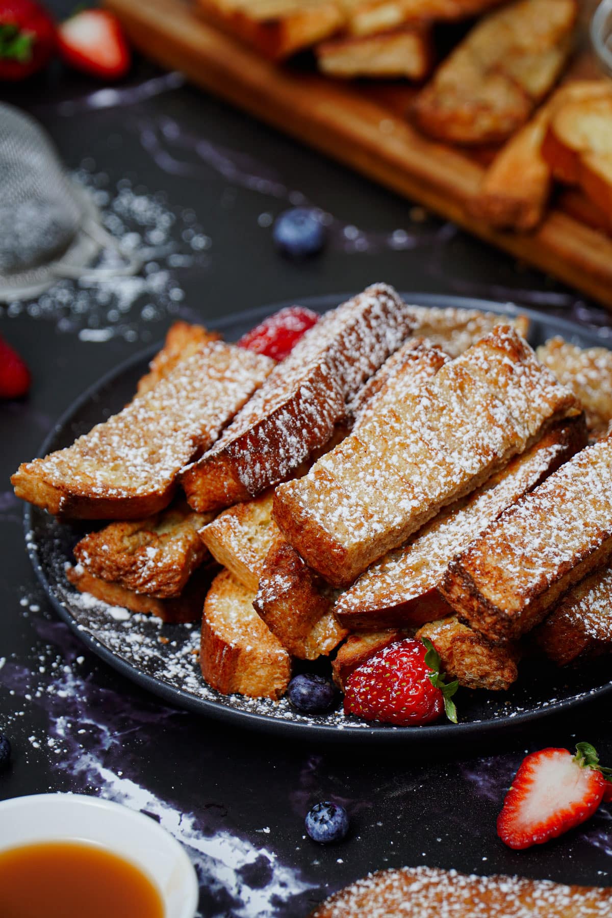 Air fryer French toast sticks recipe bite shot, served with caramel dipping sauce and berries.