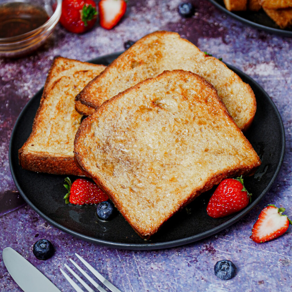 Air fryer French toast served with berries and maple syrup.