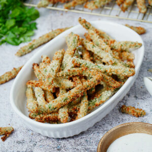 Air fryer green bean fries served on a baking dish with ranch dipping sauce.