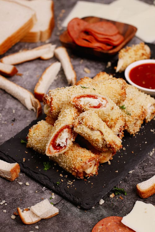 Air fryer pizza roll ups recipe bite shot, served on a black stone with pizza dipping sauce
