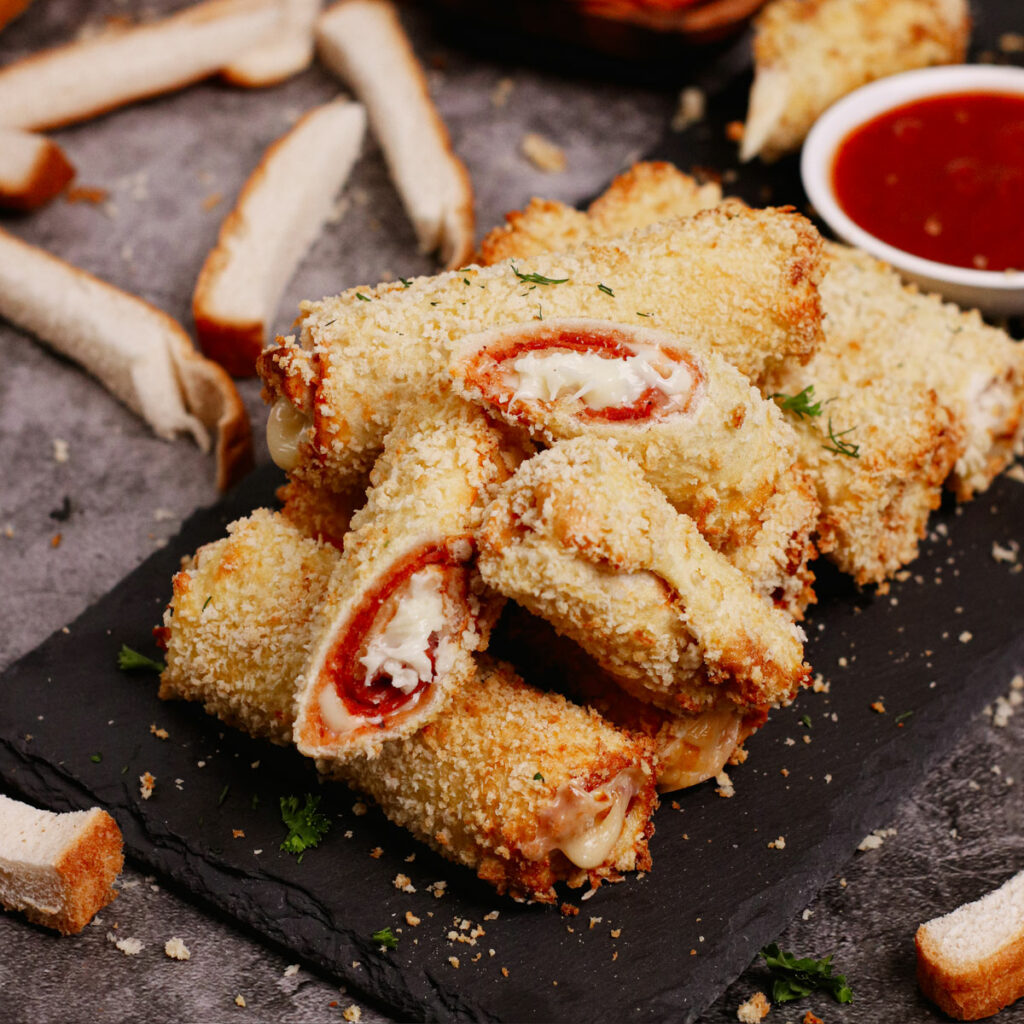 Air fryer pizza roll ups served on a black stone with pizza sauce