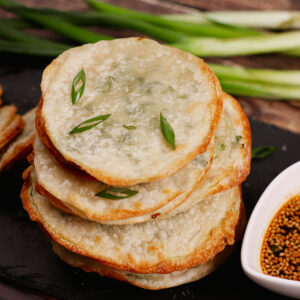 Stacked air fryer scallion pancakes with dipping sauce on the side